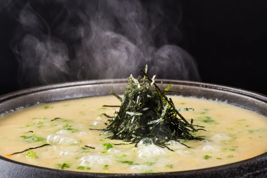 三燔本家推出的「頂級鱈場蟹饗宴」中，壓軸登場的鱈蟹膏雜炊是將蟹鍋精華湯底加入噴香米飯與濃郁蟹膏一同熬煮，起鍋前淋上蛋液並灑上海苔絲及蔥花，美味而充滿飽足感。圖/台北晶華提供