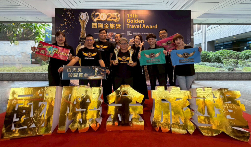 百夫長團隊手持雙金獎座與品牌旗幟合影，象徵今年再度創下亮眼旅遊成果。