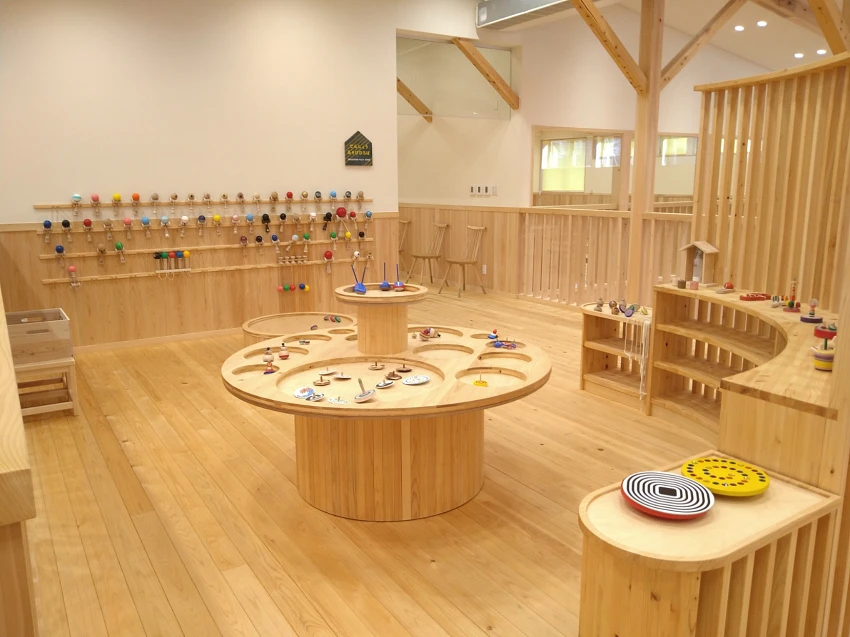 木製圓桌與多樣化的遊具器材，展示各種木質玩具，在安全環境中盡情動手探索與學習。©檜原森のおもちゃ美術館
